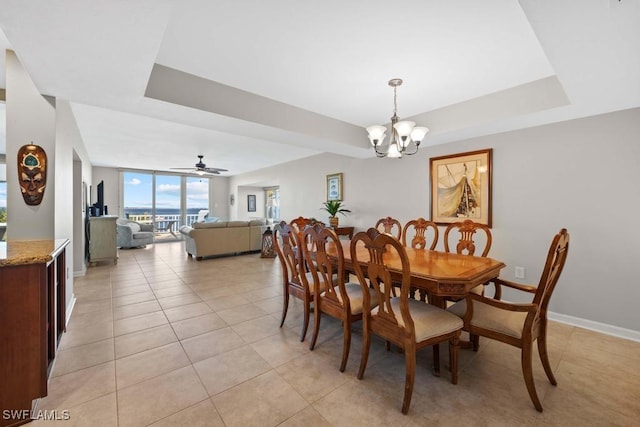 dining space featuring a tray ceiling, floor to ceiling windows, light tile patterned floors, and ceiling fan with notable chandelier