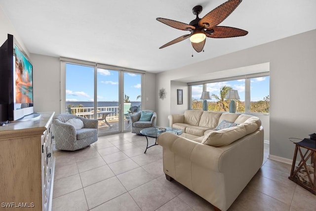 living room with a wealth of natural light, a water view, light tile patterned floors, and ceiling fan