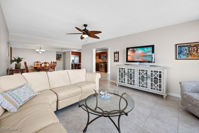 tiled living room with ceiling fan with notable chandelier