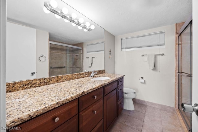 bathroom featuring tile patterned flooring, vanity, toilet, and an enclosed shower