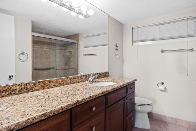 bathroom with toilet, vanity, tile patterned floors, and a shower with door