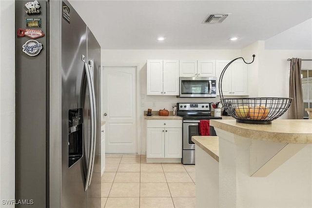 kitchen featuring stainless steel appliances, light tile patterned floors, and white cabinets