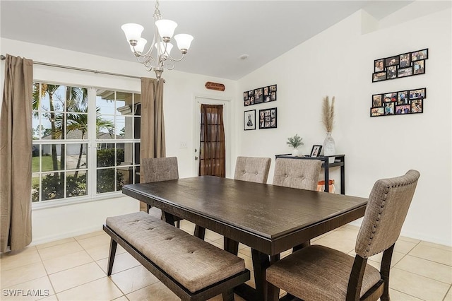 tiled dining area featuring a notable chandelier and lofted ceiling