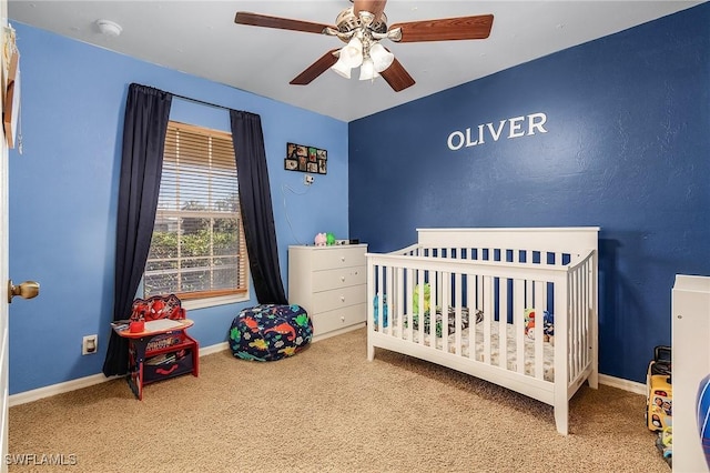 carpeted bedroom featuring a nursery area and ceiling fan