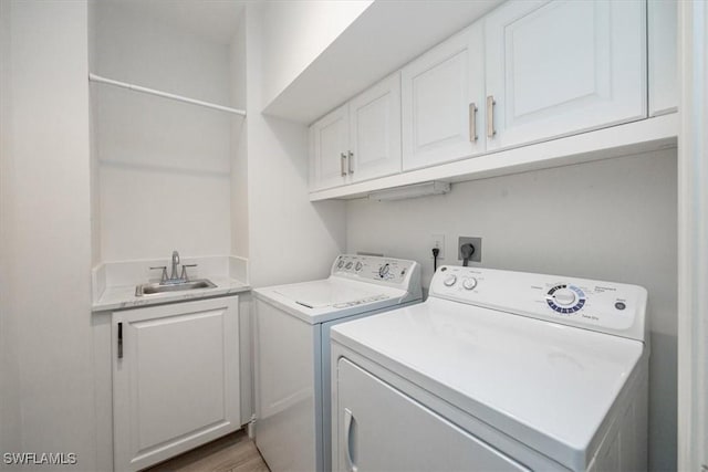 laundry area with cabinets, separate washer and dryer, sink, and hardwood / wood-style floors