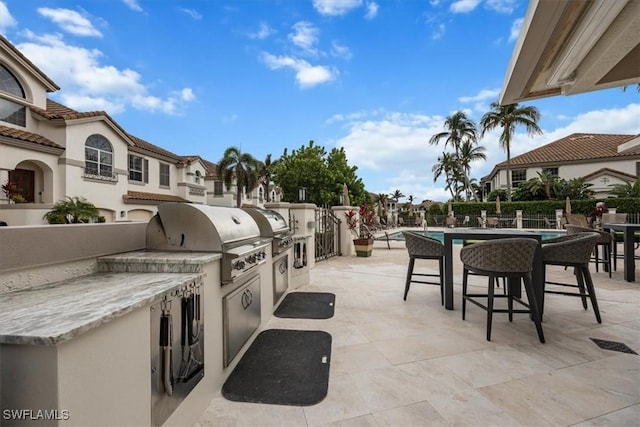 view of patio with exterior kitchen and a grill