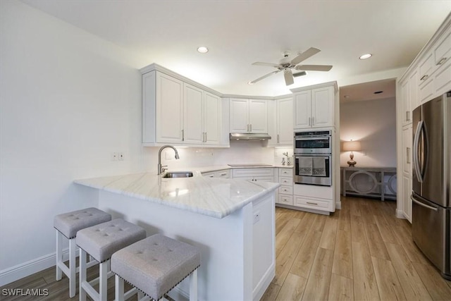 kitchen with stainless steel appliances, a kitchen breakfast bar, kitchen peninsula, and sink