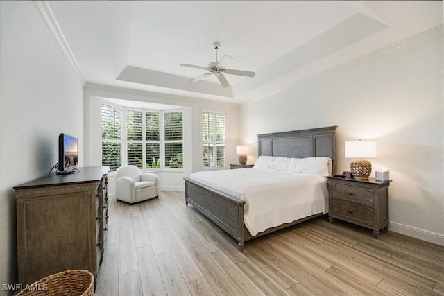 bedroom featuring crown molding, ceiling fan, a tray ceiling, and light wood-type flooring