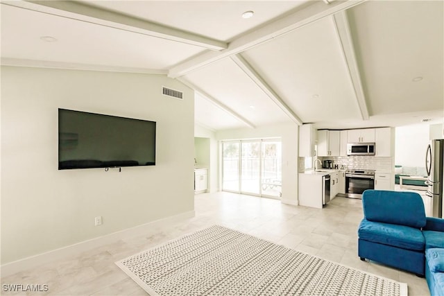 living room featuring light tile patterned floors, vaulted ceiling with beams, and sink