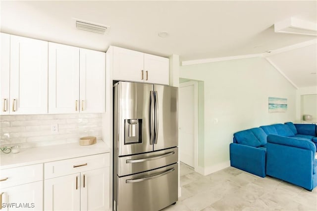 kitchen featuring white cabinets, stainless steel fridge, tasteful backsplash, and lofted ceiling