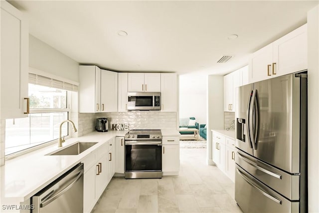 kitchen with backsplash, sink, white cabinetry, and stainless steel appliances