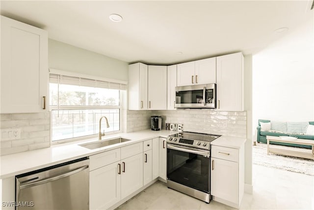 kitchen with white cabinets, appliances with stainless steel finishes, backsplash, and sink