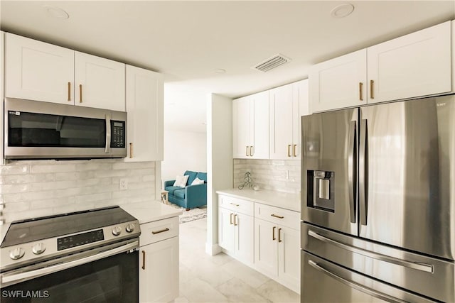 kitchen featuring tasteful backsplash, white cabinetry, light stone countertops, and appliances with stainless steel finishes