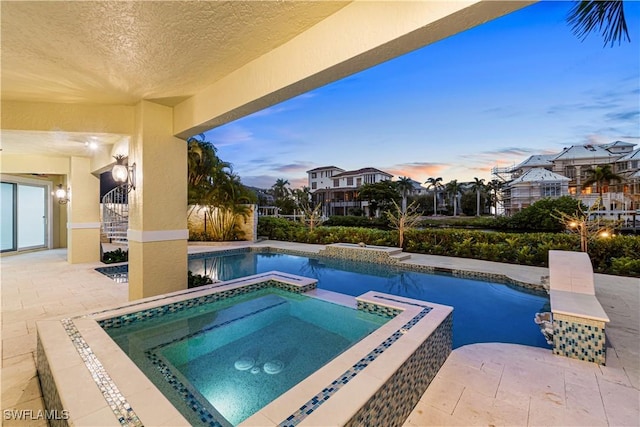 pool at dusk with an in ground hot tub