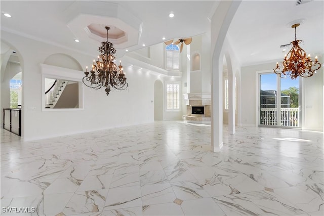 unfurnished living room featuring a chandelier, a healthy amount of sunlight, and crown molding