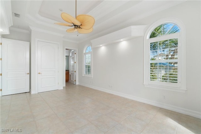 tiled empty room with ceiling fan, a raised ceiling, and crown molding