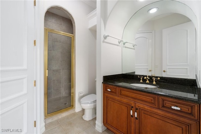 bathroom featuring toilet, vanity, tile patterned floors, and a shower with door