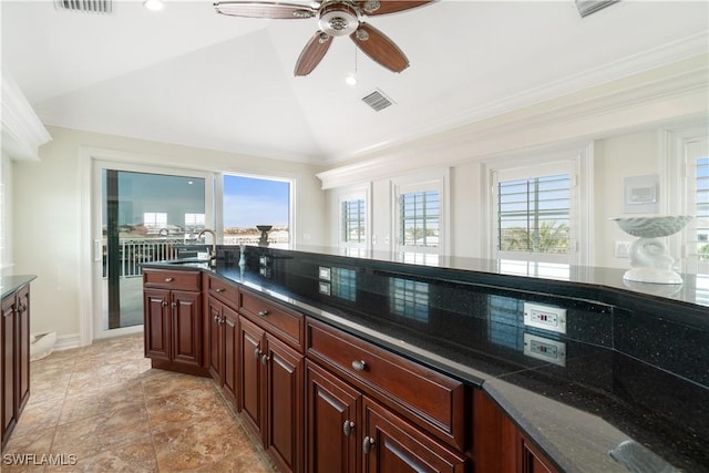 kitchen with ceiling fan, sink, dark stone countertops, lofted ceiling, and ornamental molding