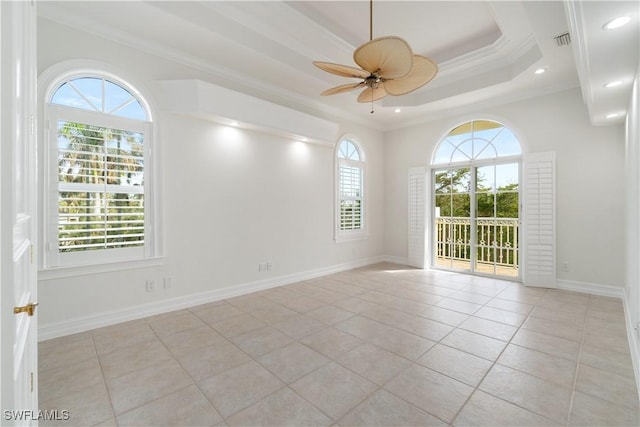 tiled spare room featuring a healthy amount of sunlight, a tray ceiling, ceiling fan, and ornamental molding