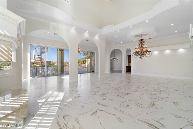 spare room featuring a notable chandelier, crown molding, and a high ceiling