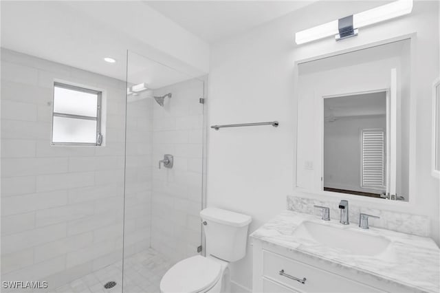 bathroom featuring vanity, toilet, and a tile shower