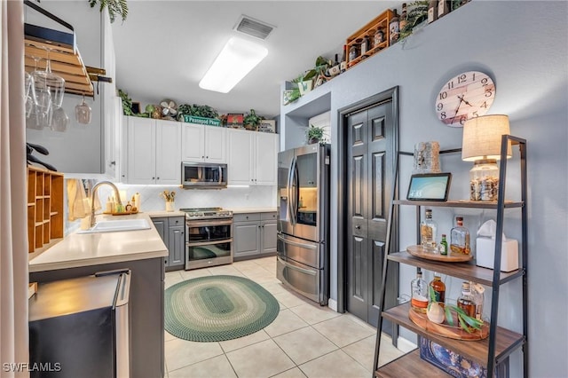 kitchen with sink, gray cabinets, appliances with stainless steel finishes, tasteful backsplash, and white cabinetry