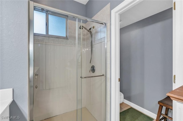 bathroom featuring tile patterned flooring, toilet, and walk in shower