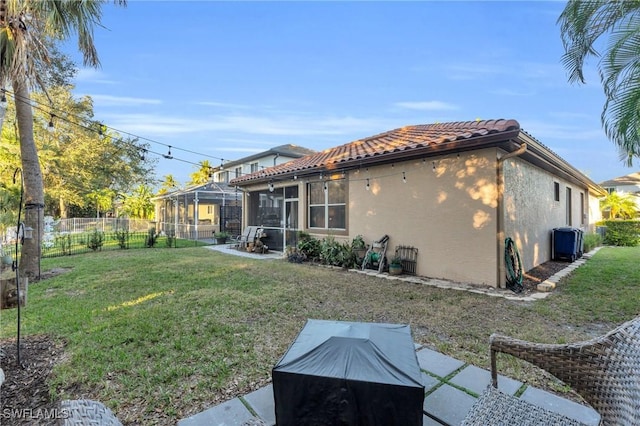 back of property featuring glass enclosure and a yard