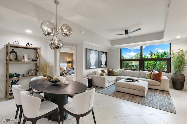 tiled dining area with ceiling fan and a tray ceiling