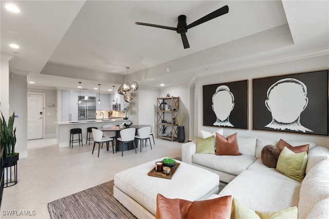 living room with crown molding, sink, ceiling fan, and a tray ceiling