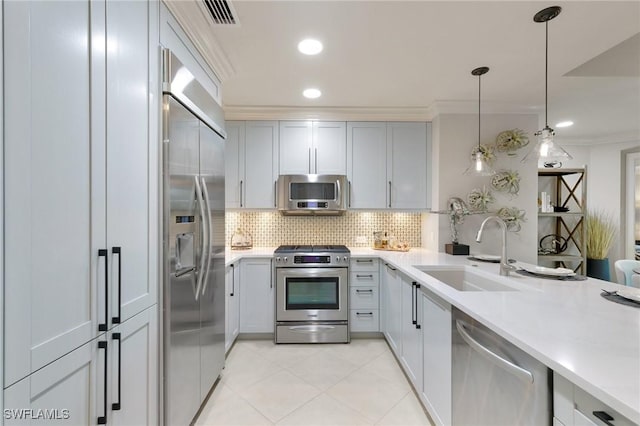 kitchen with sink, decorative backsplash, hanging light fixtures, ornamental molding, and stainless steel appliances