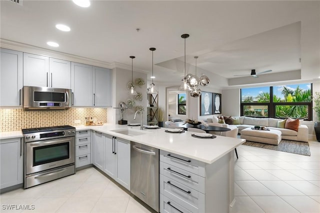 kitchen featuring stainless steel appliances, tasteful backsplash, sink, and kitchen peninsula