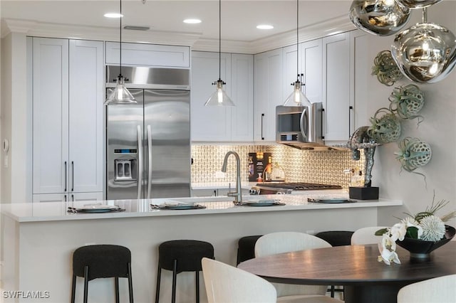 kitchen with white cabinetry, appliances with stainless steel finishes, kitchen peninsula, pendant lighting, and decorative backsplash