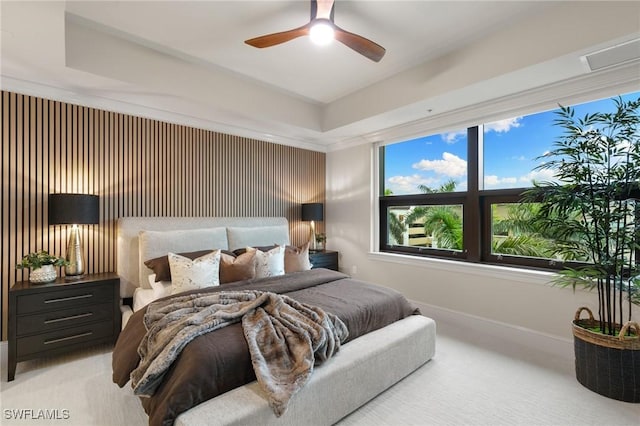 bedroom with light carpet, a tray ceiling, and ceiling fan