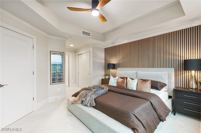 bedroom with a raised ceiling, ornamental molding, light colored carpet, and ceiling fan