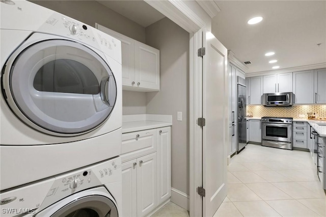 washroom with stacked washer and dryer and light tile patterned floors