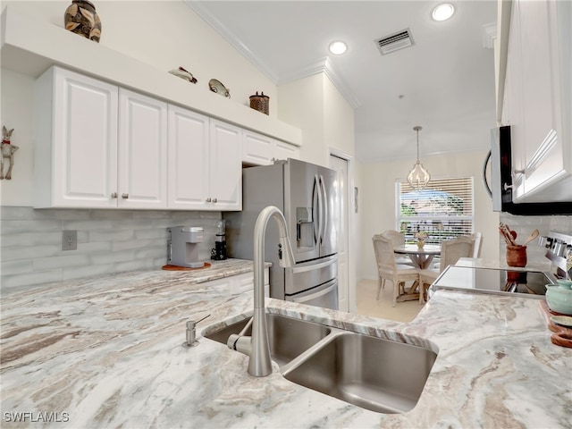 kitchen featuring white cabinetry, light stone countertops, backsplash, decorative light fixtures, and appliances with stainless steel finishes