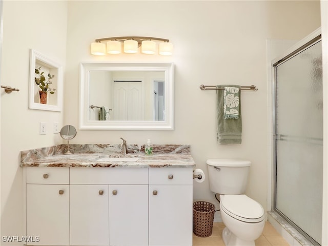 bathroom featuring tile patterned floors, a shower with door, vanity, and toilet