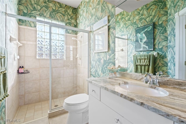 bathroom featuring tile patterned flooring, vanity, toilet, and a shower with door