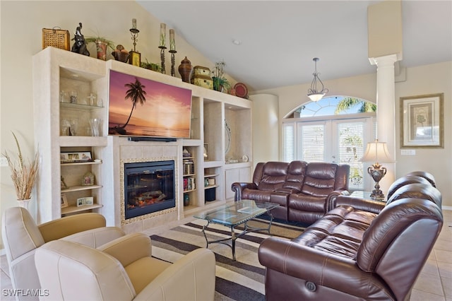 living room featuring built in shelves, a tile fireplace, decorative columns, lofted ceiling, and light tile patterned floors