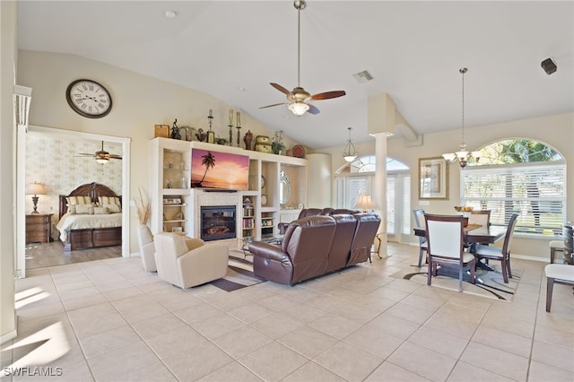 living room with lofted ceiling, ceiling fan with notable chandelier, light tile patterned floors, a fireplace, and decorative columns