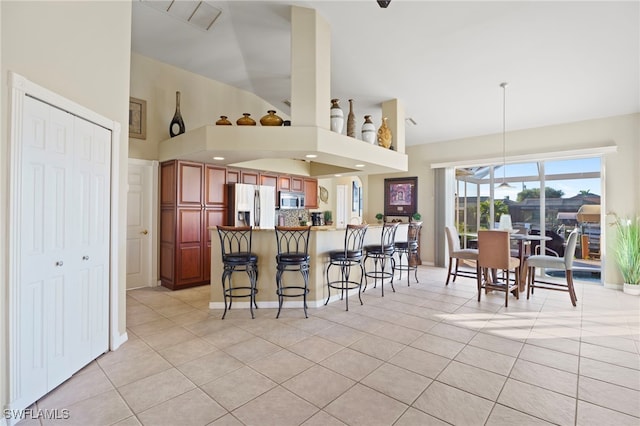 kitchen with a kitchen bar, light tile patterned floors, kitchen peninsula, and appliances with stainless steel finishes