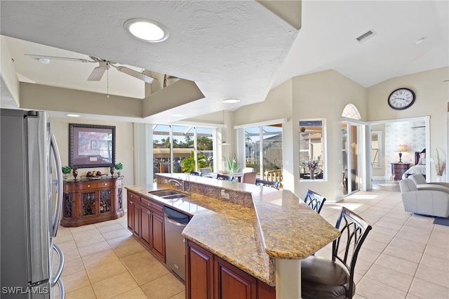 kitchen with sink, light tile patterned floors, stainless steel appliances, and a breakfast bar area