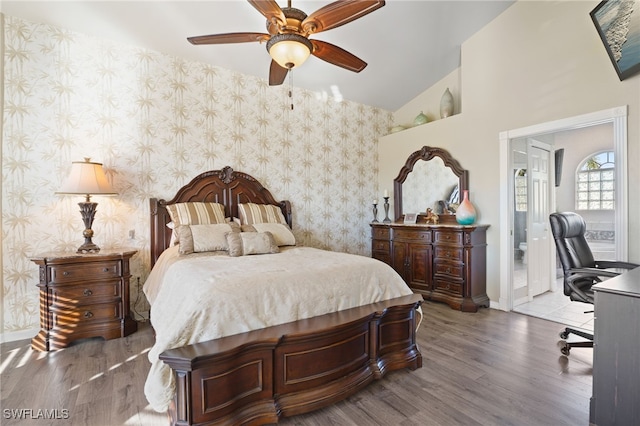 bedroom featuring hardwood / wood-style flooring, ceiling fan, ensuite bath, and vaulted ceiling