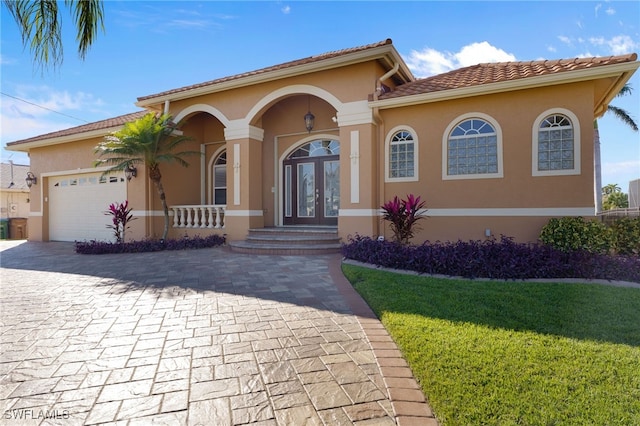 mediterranean / spanish house featuring french doors, a garage, and a front lawn