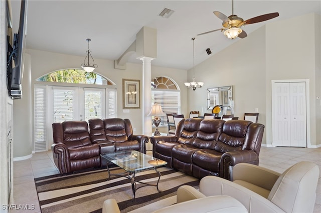 living room with ceiling fan with notable chandelier, light tile patterned flooring, ornate columns, and high vaulted ceiling