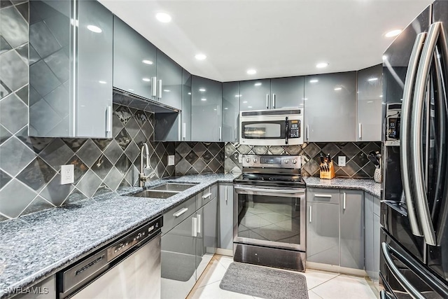 kitchen with light stone counters, sink, light tile patterned floors, and stainless steel appliances