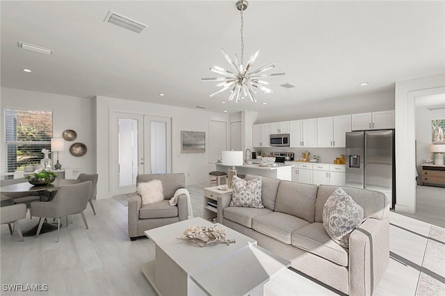 living room with french doors, light wood-type flooring, and a notable chandelier