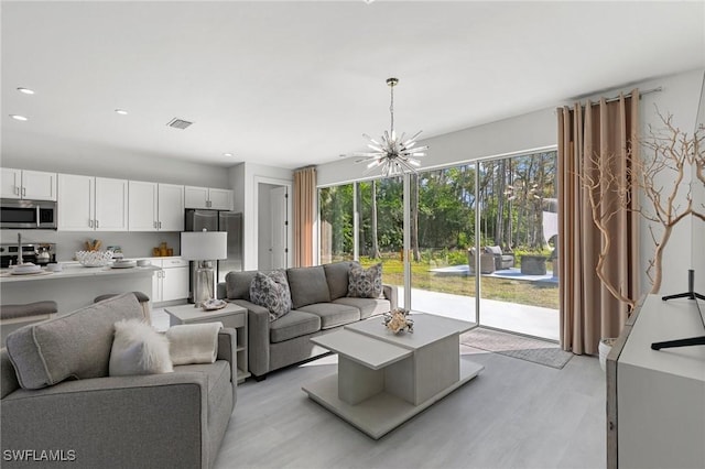 living room with light wood-type flooring and an inviting chandelier