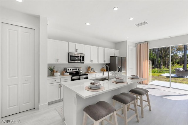 kitchen with white cabinets, sink, a breakfast bar area, an island with sink, and stainless steel appliances